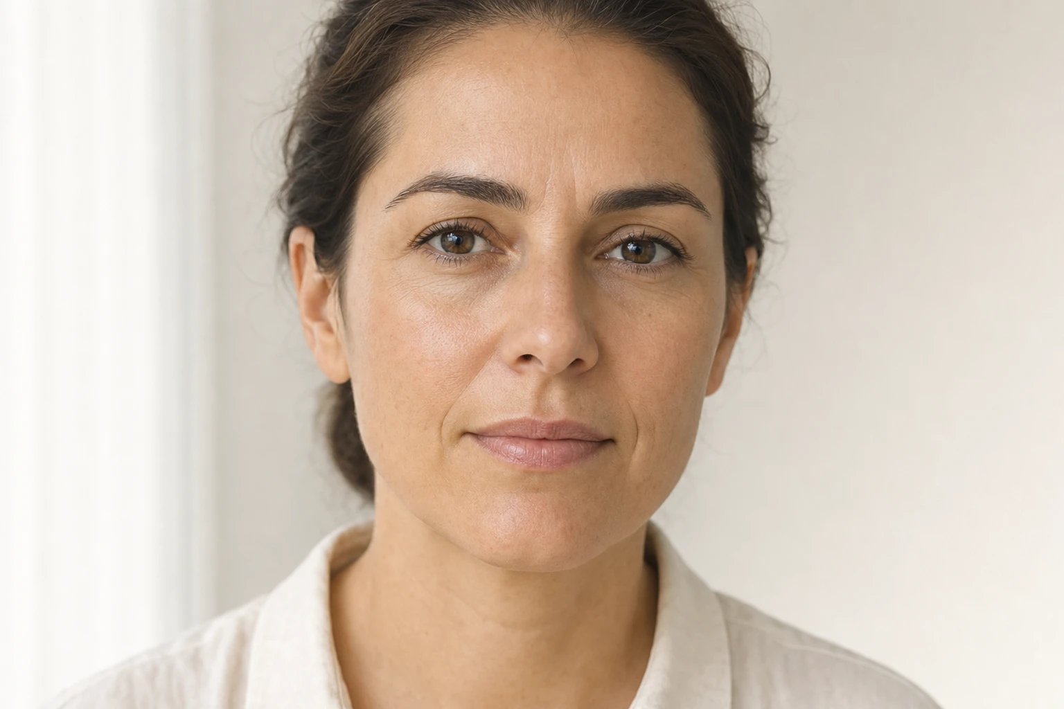 Visage au repos d'une femme fictive, expression neutre et naturelle, avec un pli vertical visible mais non exagéré entre les sourcils.